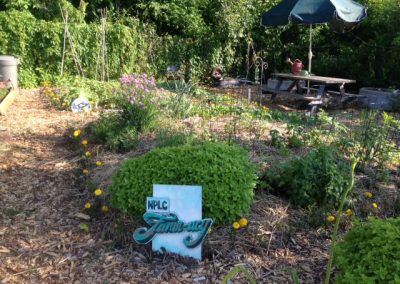 Large community garden with NPLC Farm-acy sign